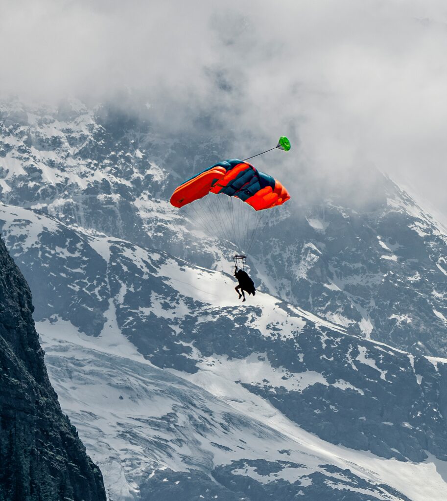 Flyer in a red suit over snowy mountains